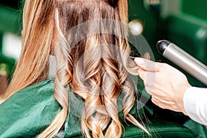 Hairdresser`s hands twisting hair of woman