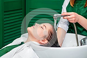 Hairdresser`s hands washing hair of woman