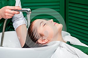 Hairdresser`s hands washing hair of woman