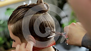 At the hairdresser`s, woman getting her hair done in the beauty salon by male hairdresser. Professional stylist cutting