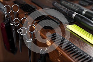 Hairdresser`s workplace. A set of scissors, combs, nozzles for cutting hair of a machine, on a wooden table in a barbershop