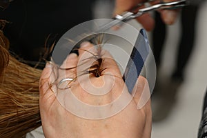 Hairdresser with scissors and comb in hand that is cutting hair