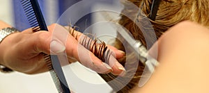 Hairdresser with scissors and comb in hand that is cutting hair