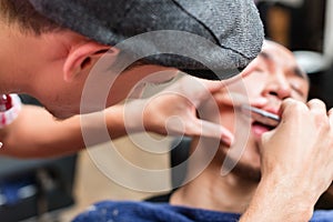 Hairdresser shaving man`s moustache