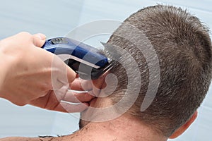 Hairdresser smoothes and shortens the hair on the manâ€™s head in the bathroom