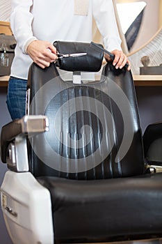 hairdresser stood holding scissors behind empty chair