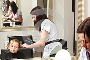 Hairdresser straightening hair little girl child in hairdressing beauty salon