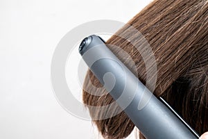 Hairdresser straightening long dark hair with hair irons