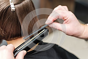 Hairdresser straightening short brown hair with hair irons