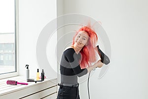 Hairdresser, style, people concept - woman is blowing dry her colored hair