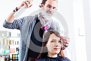 Hairdresser styling woman hair in shop