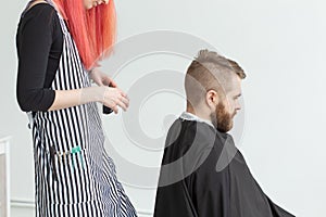 Hairdresser, stylist and barber shop concept - woman hairstylist cutting a man