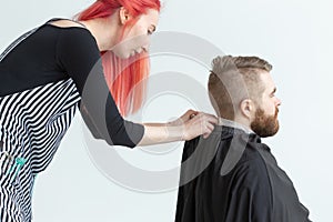 Hairdresser, stylist and barber shop concept - woman hairstylist cutting a man