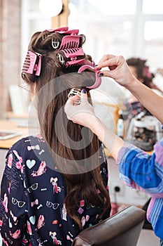 Hairdresser taking off curlers from woman long hair
