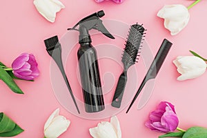 Hairdresser tools - spray, combs and tulips flowers on pink background. Beauty concept. Flat lay, top view
