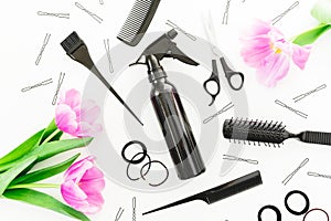 Hairdresser tools - spray, scissors, combs, barrette and tulips flowers on white background. Beauty concept. Flat lay, top view