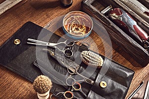 Hairdresser tools on wooden background. Top view on wooden table with scissors, comb, hairbrushes and hairclips, trimmer