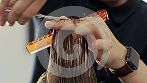 Hairdresser trimming brown hair with scissors. Professional stylist cutting woman`s hair in salon, closeup. Close up of