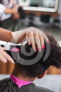 Hairdresser trimming hair of african american