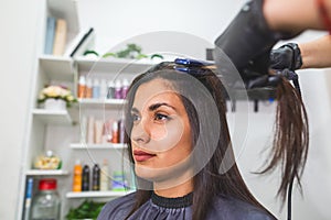 Hairdresser using a hair straightened to straighten the hair. Hair stylist working on a woman`s hair style at salon