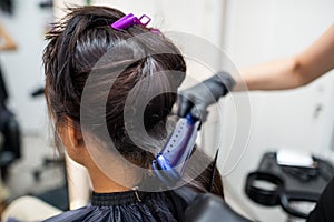 Hairdresser using a hair straightened to straighten the hair. Hair stylist working on a woman`s hair style at salon