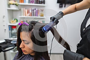 Hairdresser using a hair straightened to straighten the hair. Hair stylist working on a woman`s hair style at salon