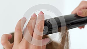 Hairdresser using hair tongs for curling close up. Process curling long hair with iron in beauty studio. Hairstylist
