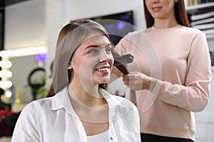 Hairdresser using straightener to style client`s hair