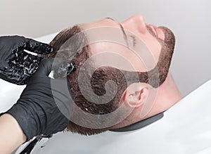 The hairdresser washes the head of the young man with shampoo after haircuts