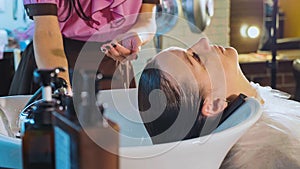 Hairdresser washes woman`s hair in the beauty studio.