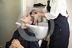 Hairdresser washes woman`s hair, hairsalon