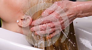 Hairdresser washing blond hair