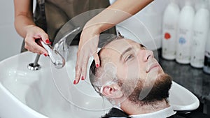 Hairdresser washing client's head with shampoo in beauty salon