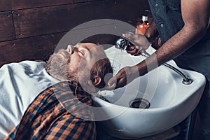 Hairdresser washing costumer head, using warm water