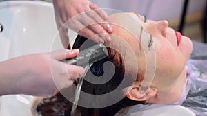 Hairdresser is washing the dye off the red hair of woman