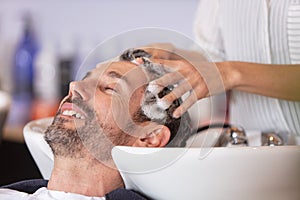 hairdresser washing hair to handsome client