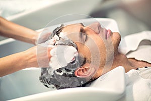 Hairdresser washing hair to her handsome client.