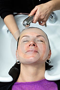 A hairdresser is washing the hair of woman in a beauty salon. Theme of beauty and hair care.