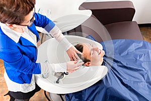 Hairdresser washing man hair in barbershop