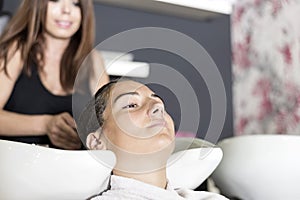 Hairdresser washing young client`s woman hair in the salon