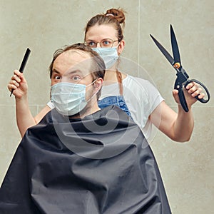 A hairdresser wife does her husband hair with garden scissors, fun concept. Self-cutting and shaving during the flu epidemic