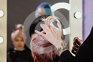 Hairdresser woman cuts her hair to a woman`s blonde woman.