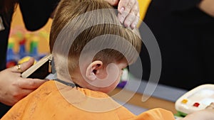 Hairdresser working with small boy in barbershop