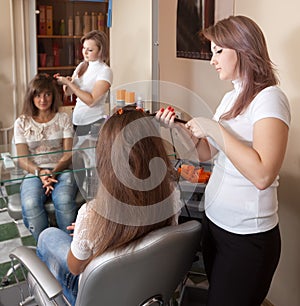 Hairdresser works on woman hair