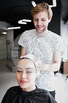 Hairdresser wrapping towel on customer`s head. Brunette woman getting hair treatment in a salon.