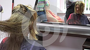 Hairdressers comb female customer hair in front of mirror. Focus change. 4K