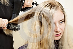Hairdressers hands drying long blond hair