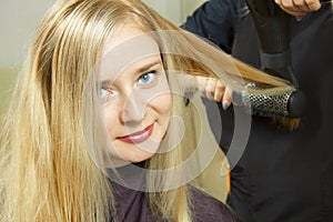 Hairdressers hands drying long blond hair