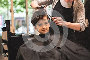 Hairdressers hands making hairstyle to child little boy in the barber shop hair cut professional - Little boy in the barber shop