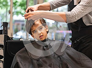Hairdressers hands making hairstyle to child little boy in the barber shop hair cut professional - Little boy in the barber shop